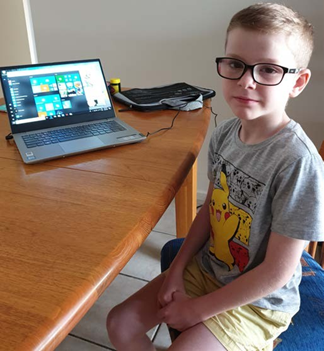 child sitting at desk with computer in background